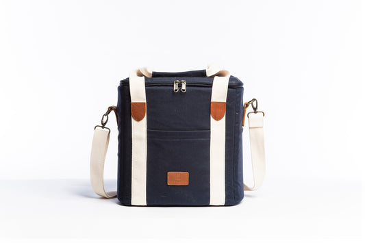 Front on image of the Slowlife Collection Navy Cooler Bag. This has a front pocket, leather detailing and a long shoulder strap included.