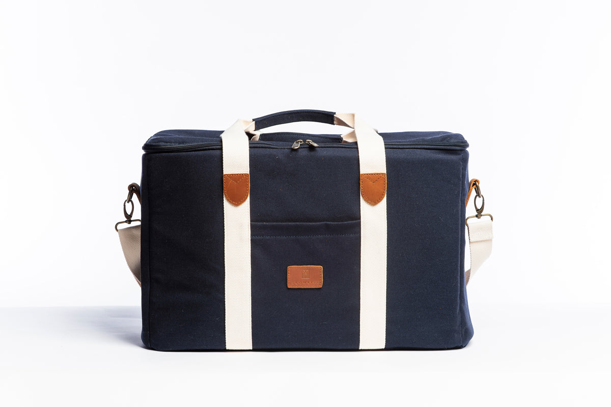 A front on photo of the Slowlife Collection Picnic Bag. Showing the cream straps with leather detailing, a front pocket and shoulder strap attached.