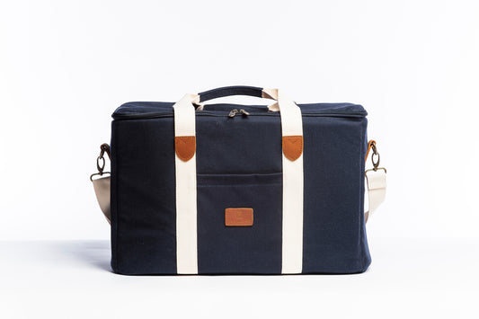A front on photo of the Slowlife Collection Picnic Bag. Showing the cream straps with leather detailing, a front pocket and shoulder strap attached.