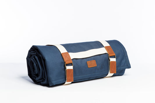 The Slowlife Collection Navy Picnic Rug rolled up side on. Showing cream handles and leather detailing.