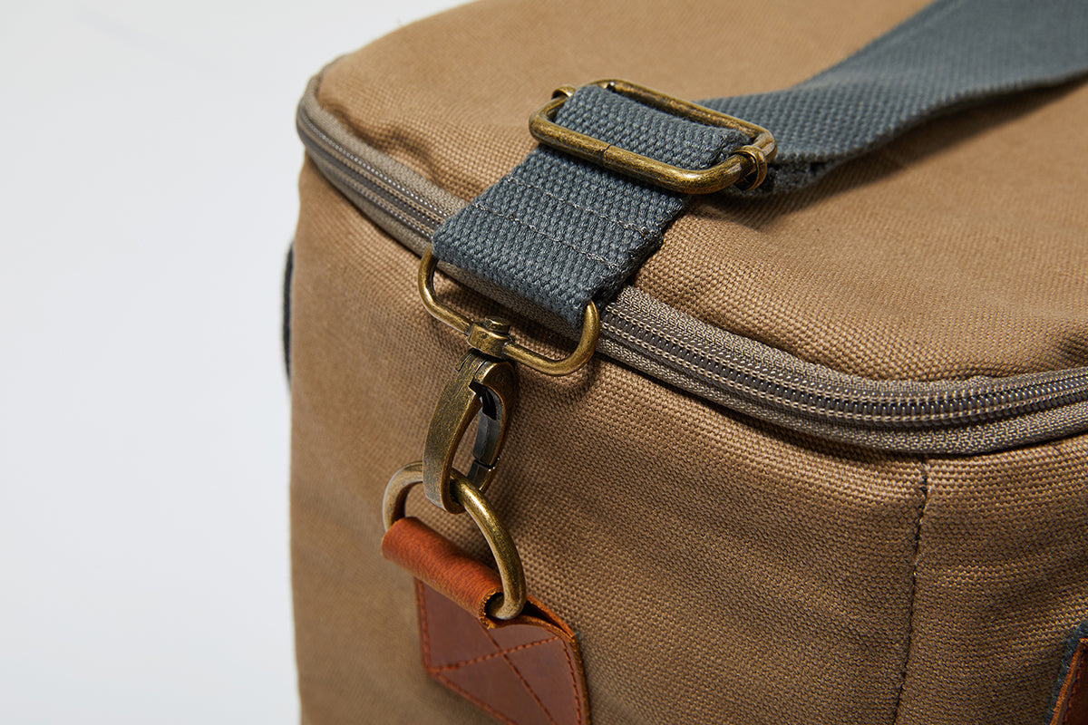 Detailing of the Slowlife Collection Olive Cooler Bag. Showing the shoulder strap clipped onto the bag with a brass clip.