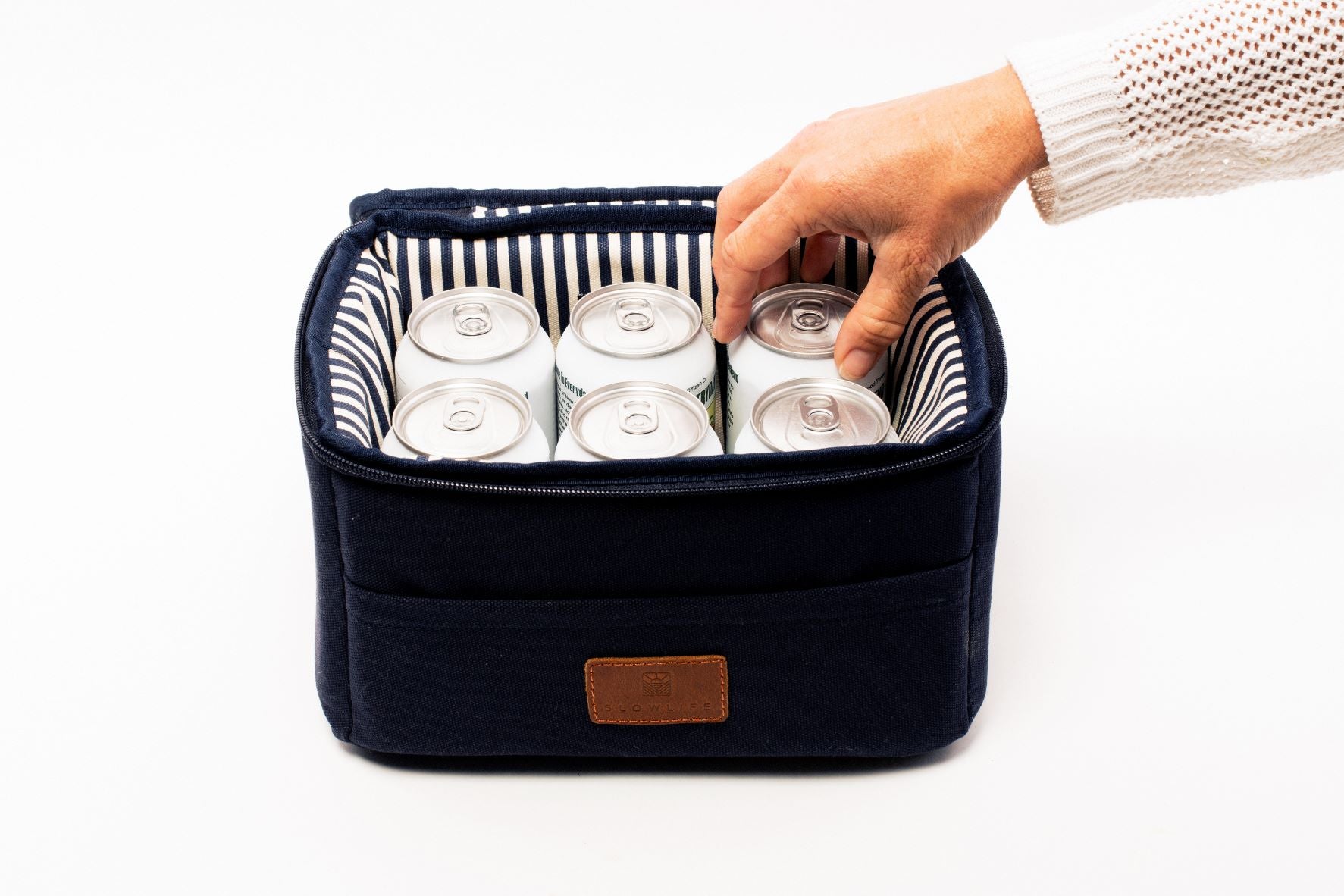 The Slowlife Collection Navy Lunch Bag with navy and cream striped lining. It has 6 cans inside and a hand reaching in to grab one out.