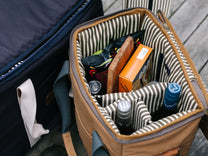 Tan cooler bag with striped interior, packed with wine and snacks.