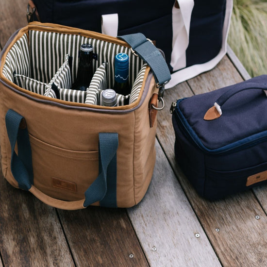 Tan cooler bag and navy lunch bag on a wooden deck.