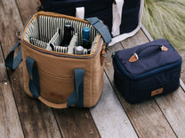 Tan cooler bag and navy lunch bag on a wooden deck.