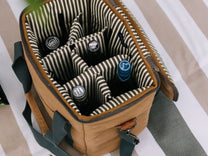 Brown cooler bag with striped interior holding bottles.