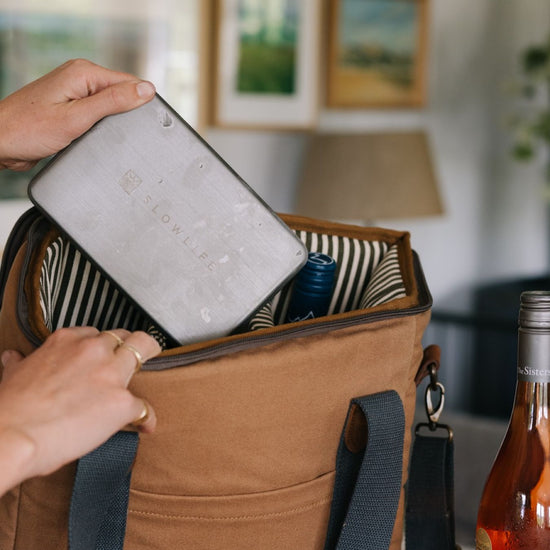 Navy cooler bag with fruit, a can, and a container inside.