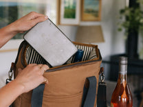 Navy cooler bag with fruit, a can, and a container inside.