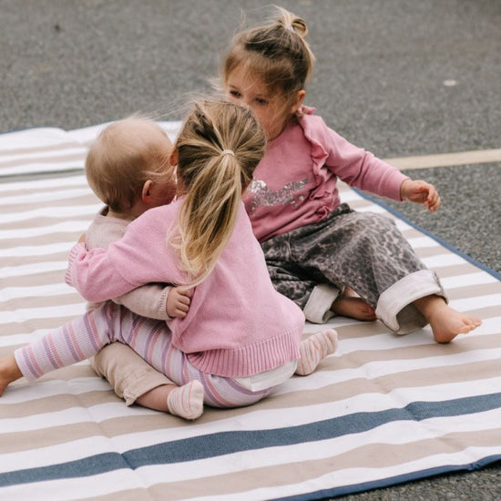 children sitting on a striped blanket