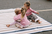 children sitting on a striped blanket