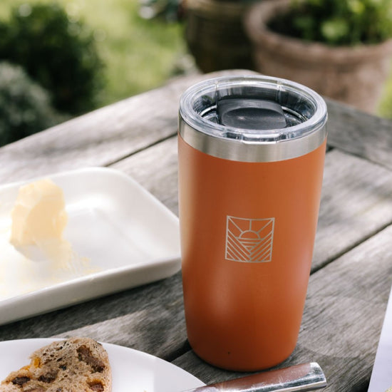 Orange insulated tumbler on a wooden table 