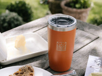 Orange insulated tumbler on a wooden table 