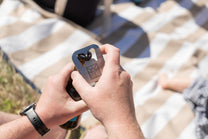 Mans hands opening a beer bottle with a Slowlife Collection bottle opener. 