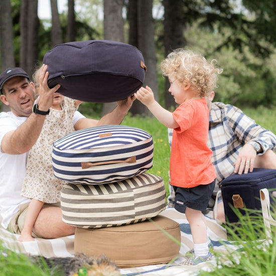 Family stacking round outdoor cushions at a picnic.
