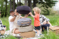 Family stacking round outdoor cushions at a picnic.
