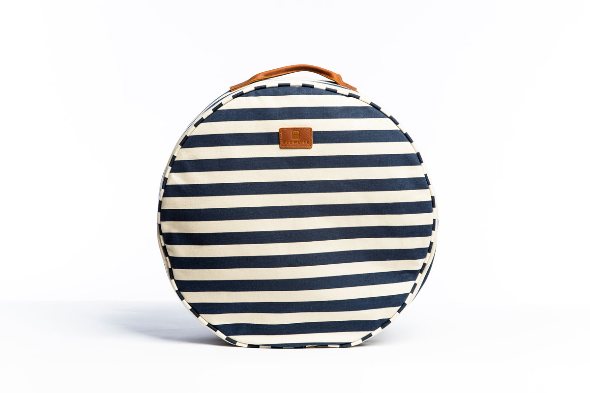 A front on photo of the Navy and cream striped Slowlife Collection cushion. Showing the leather handle and branded patch. 