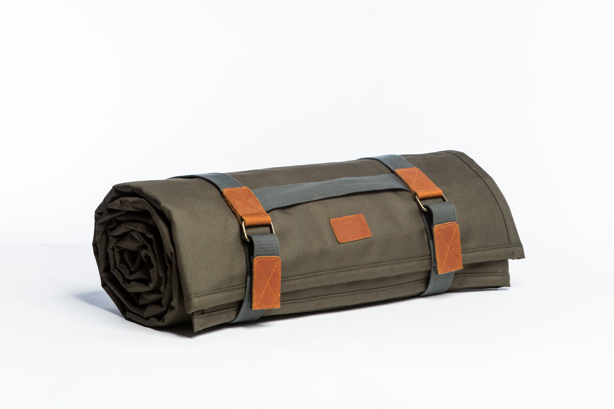The Slowlife Collection Olive Picnic Rug rolled up and side on. Showing grey handles and leather detailing.
