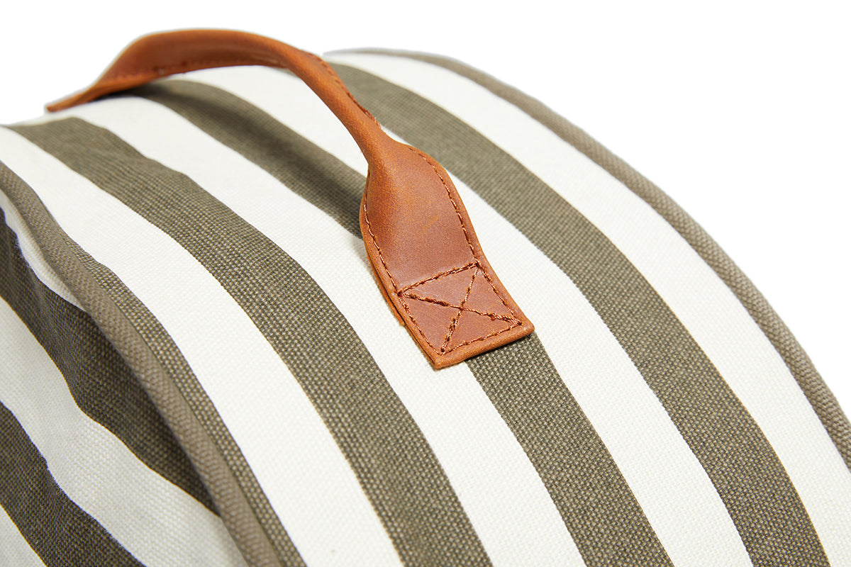 A close up of the detail on the leather handle of the Olive and cream stripe Slowlife Collection Cushion.